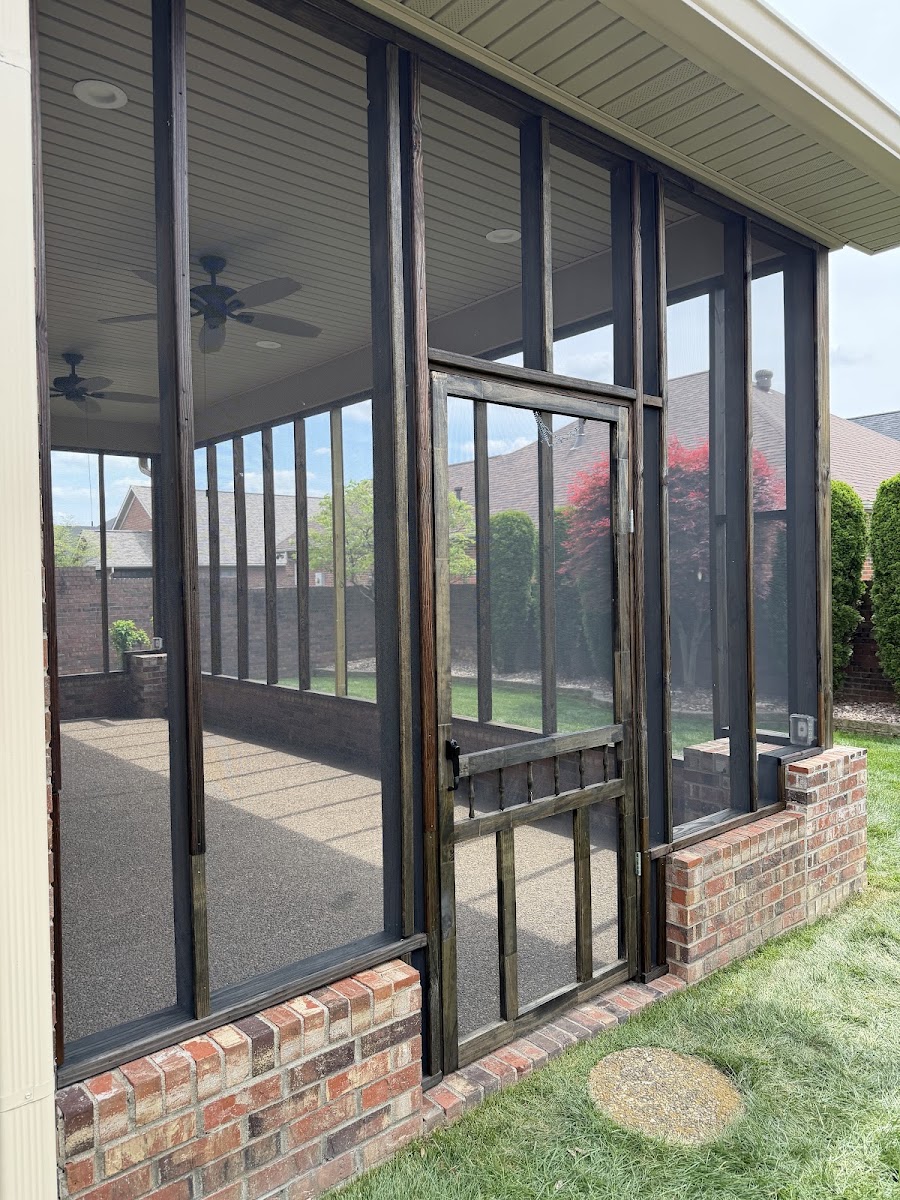 Screened porch with dark wood frames and a brick base