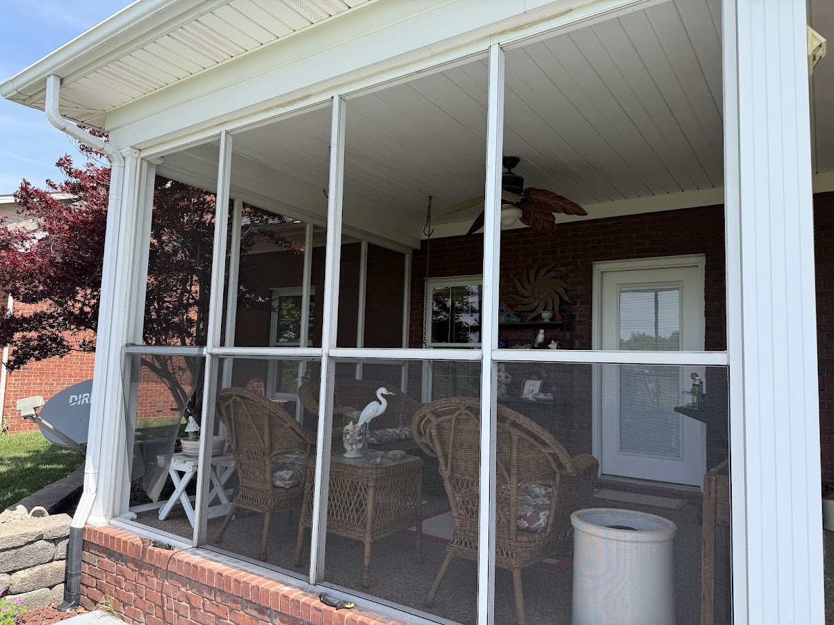 White screened porch with a ceiling fan and outdoor seating